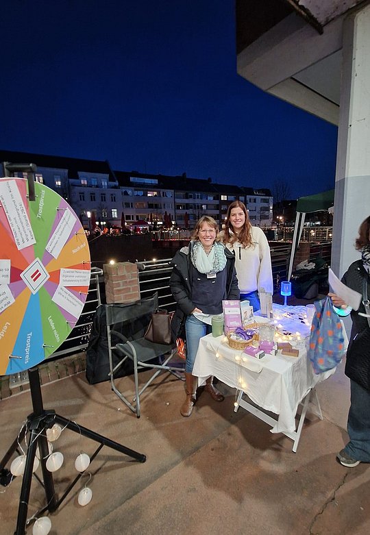 Glücksrad im Vordergrund, Mitarbeiterinnen im Hintergrund