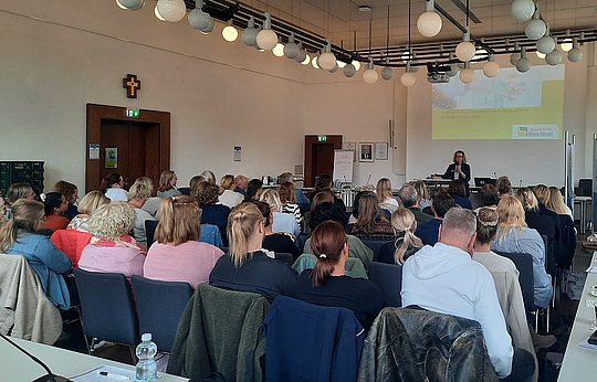 Menschen sitzen in Reihen und hören dem Vortrag zu