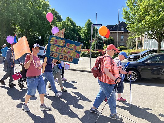 Menschen portestieren mit Schildern und Ballons