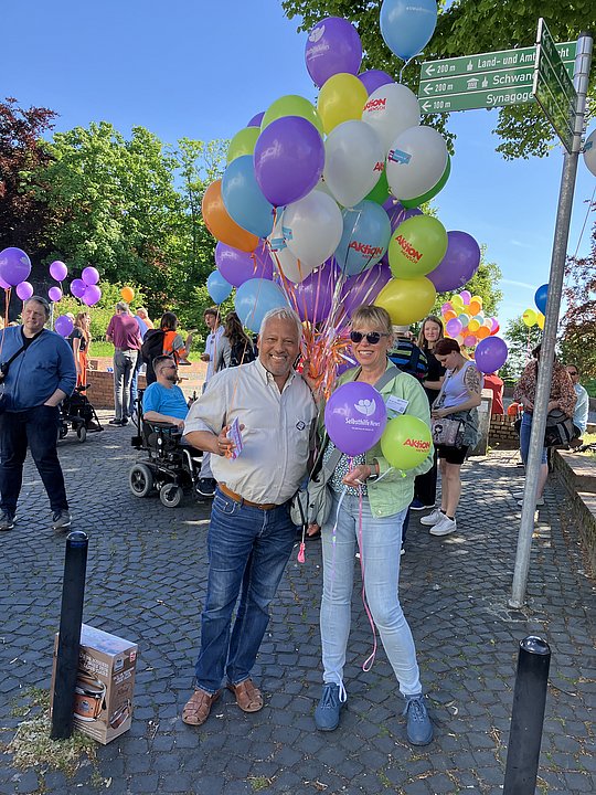 Andreas Fateh und Monika Hohlmanns halten Luftballons und schauen in die Kamera