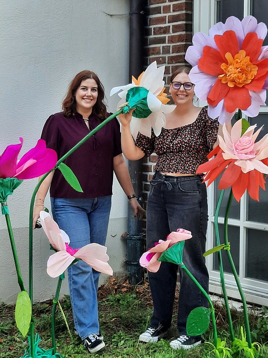 Franzi und Melina hinter Blumen aus Krebbpapier