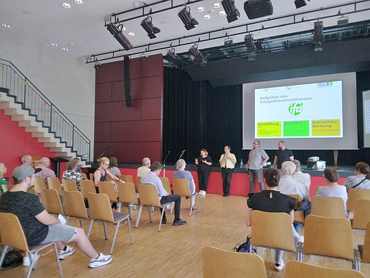 Menschen auf Stühlen lauschen der Podiumsdiskussio