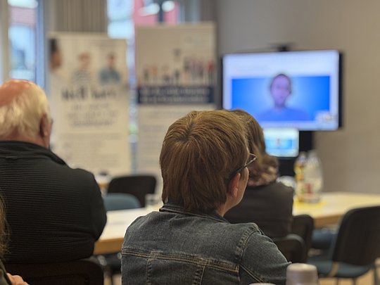 Hinterköpfe von Personen, die auf einen Bildschirm schauen