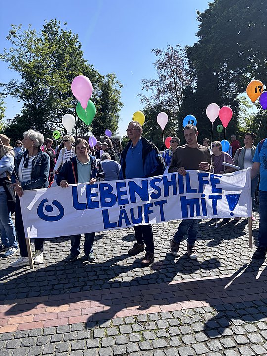 Menschen halten ein Banner der Lebenshilfe