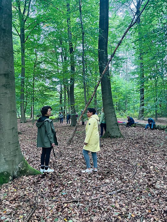 zwei Personen stehen im Wald und unterhalten sich