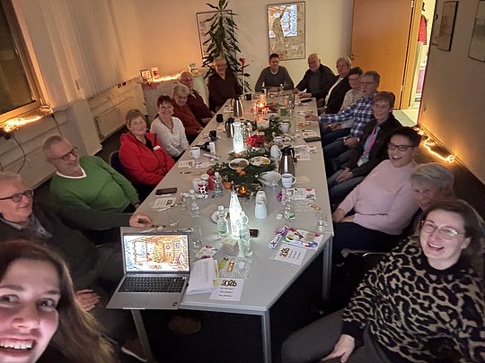 Personen am Tisch schauen in die Kamera