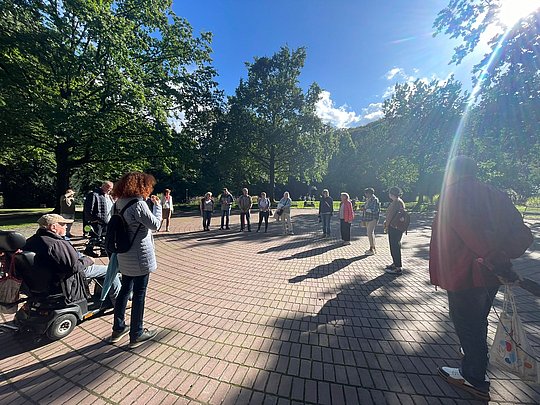 Teilnehmende stehen im Kreis. Die Sonne scheint